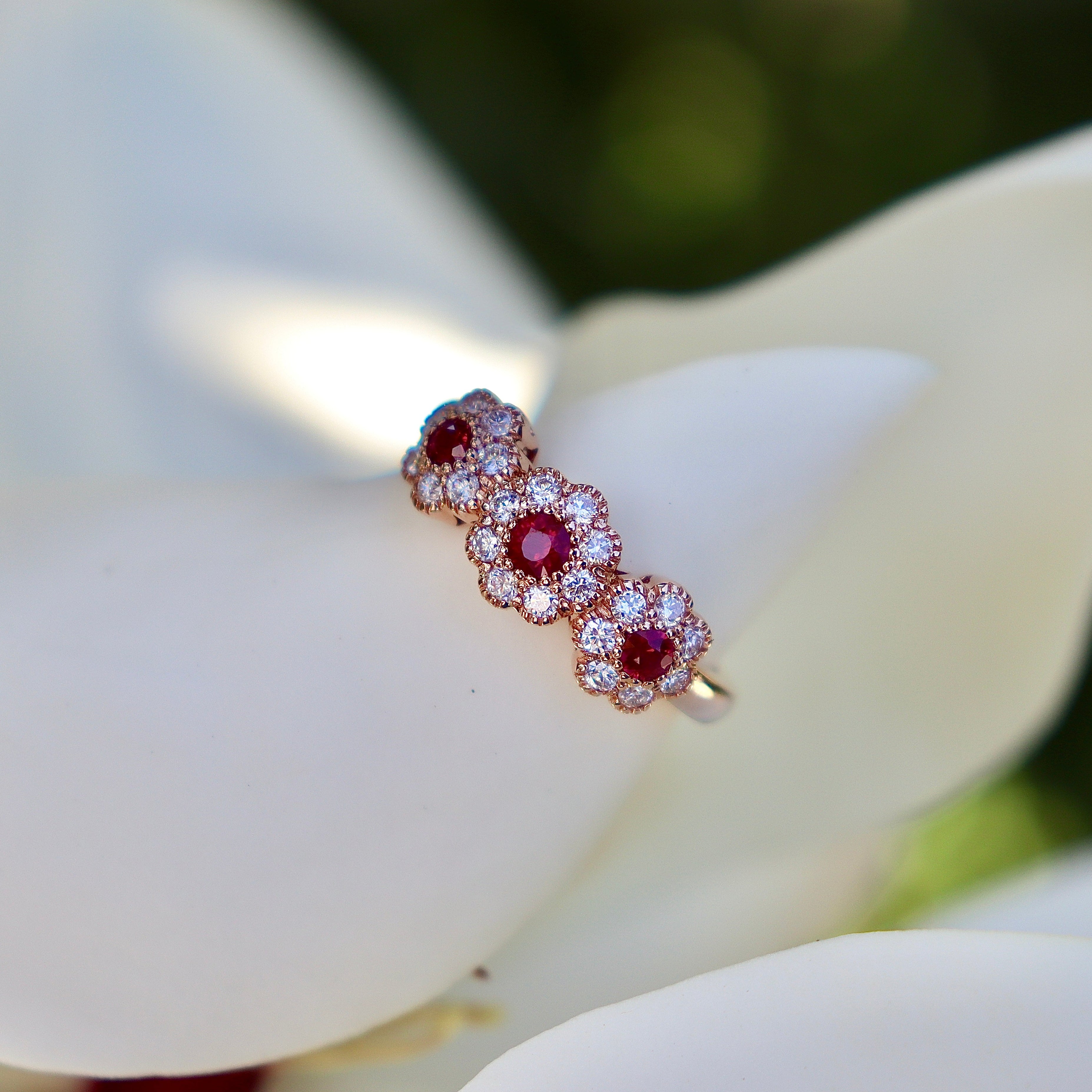 Rose gold diamond ring with ruby gemstones on a white flower petal