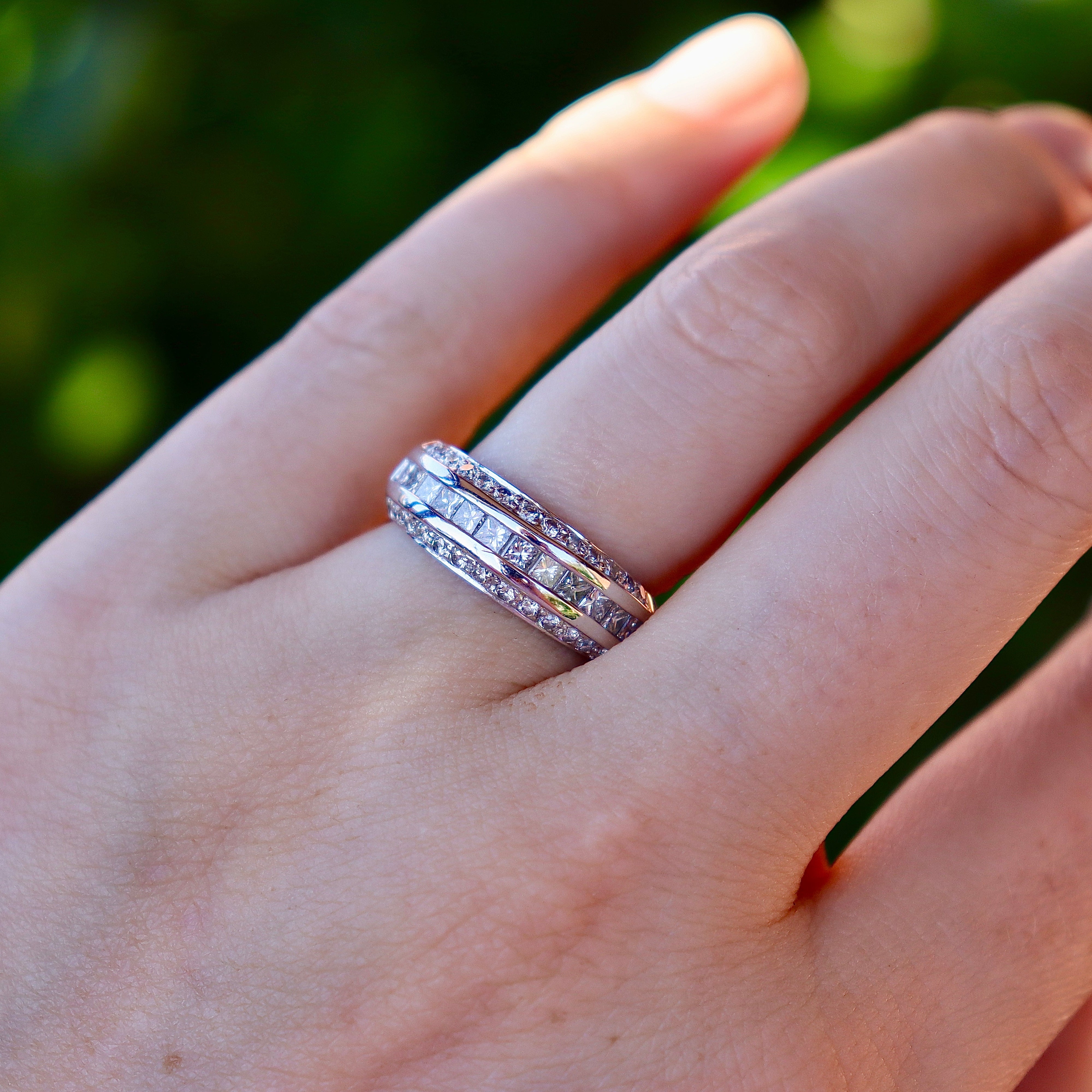 Close view of an 18ct white gold mixed-cut diamond wedding band showing brilliant and princess cuts