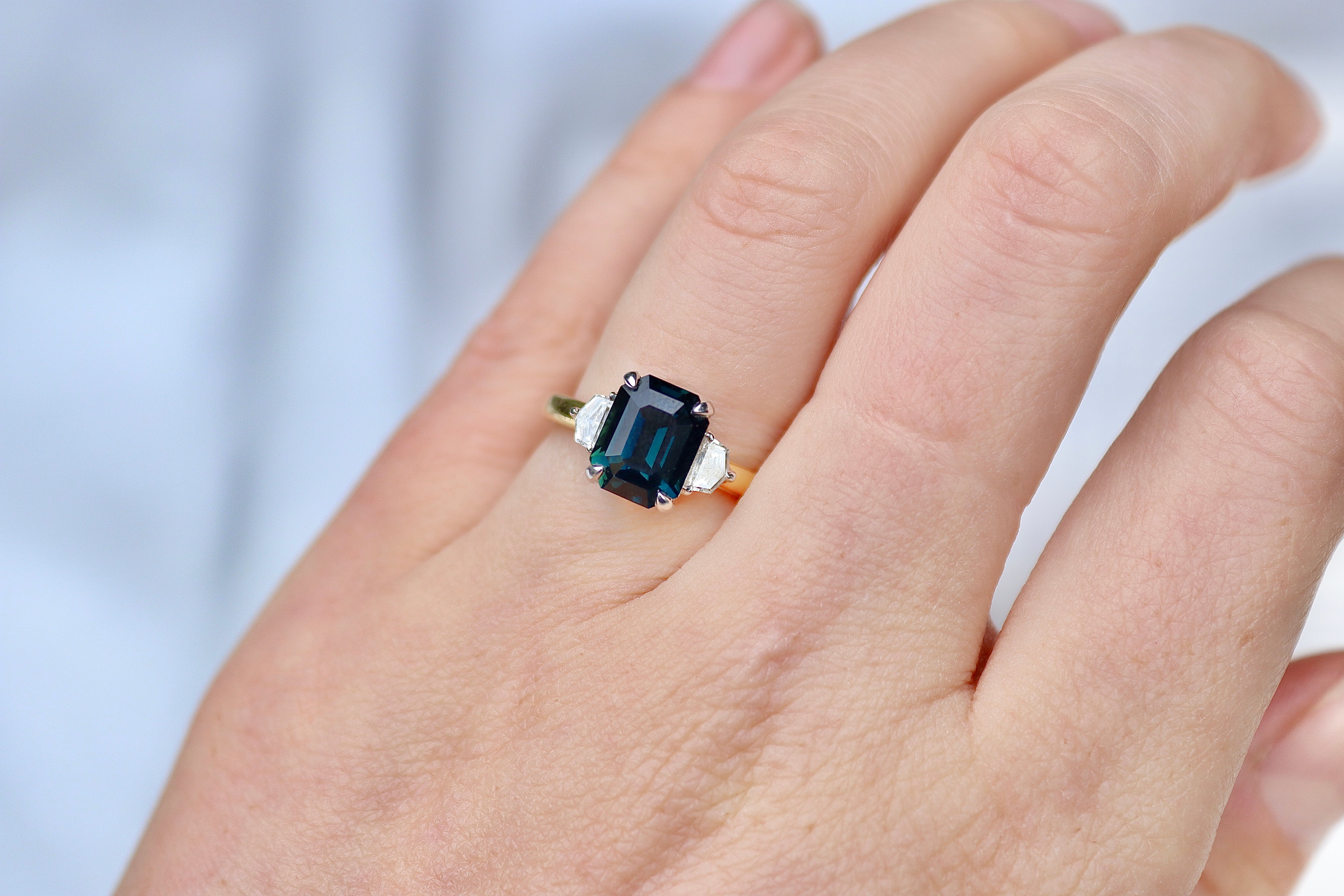 18ct Yellow and White Gold Emerald Cut Teal Sapphire and Cadillac Diamond 3 Stone Ring