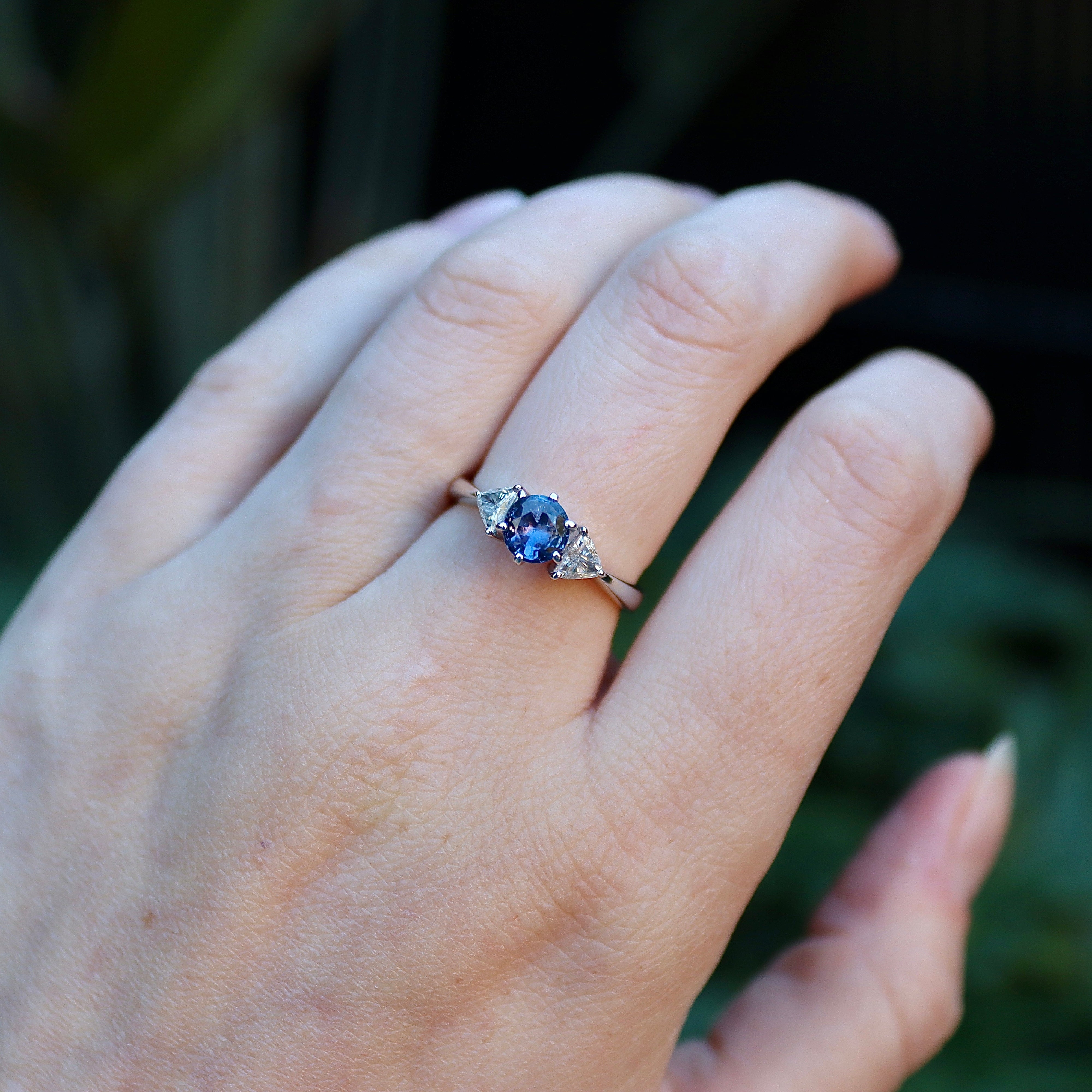 Angled view of 18ct white gold round sapphire and trillion diamond three stone ring